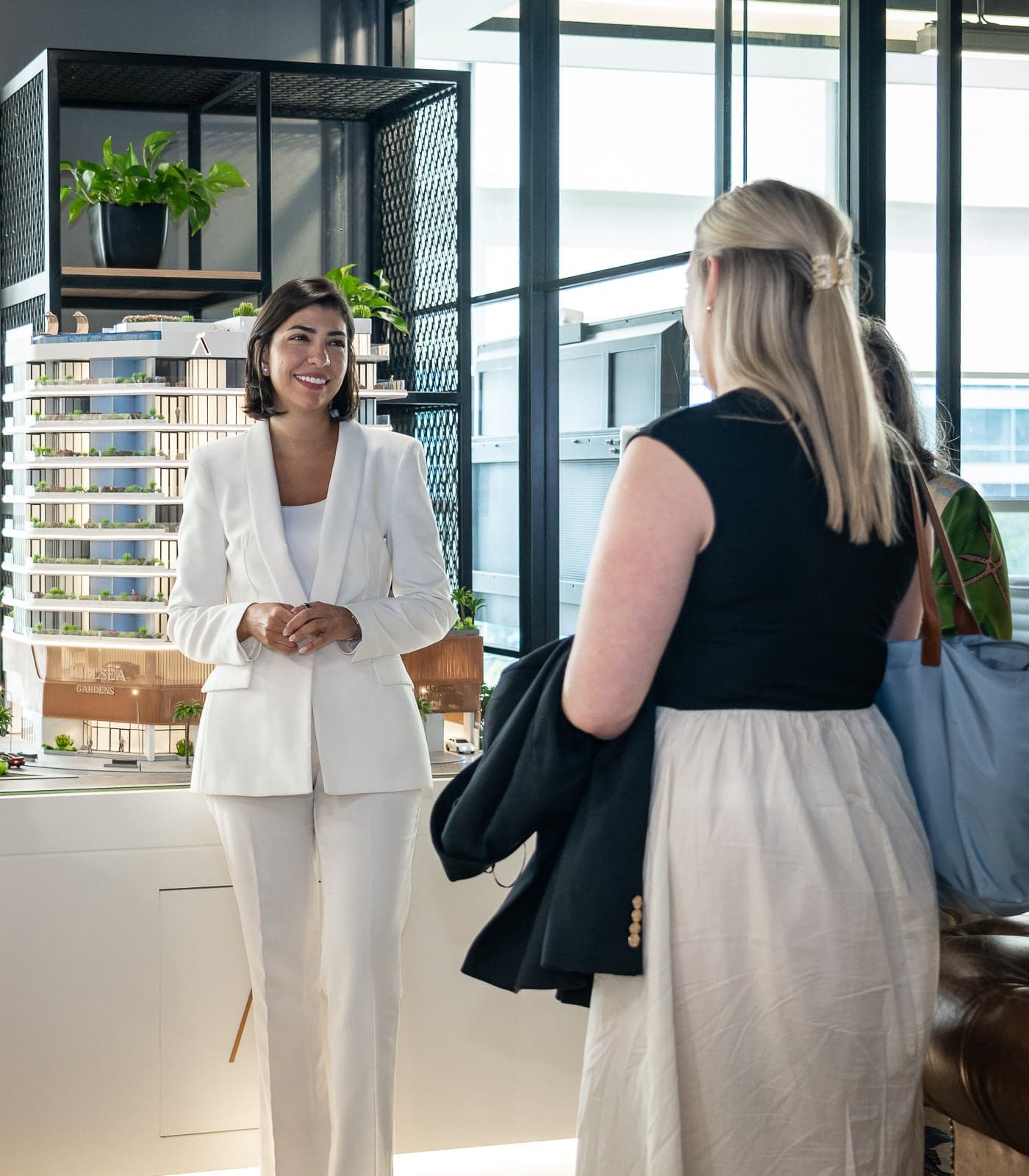 A McCone Properties agent talking with a client beside a scale model of a new tower at the office in The Greens