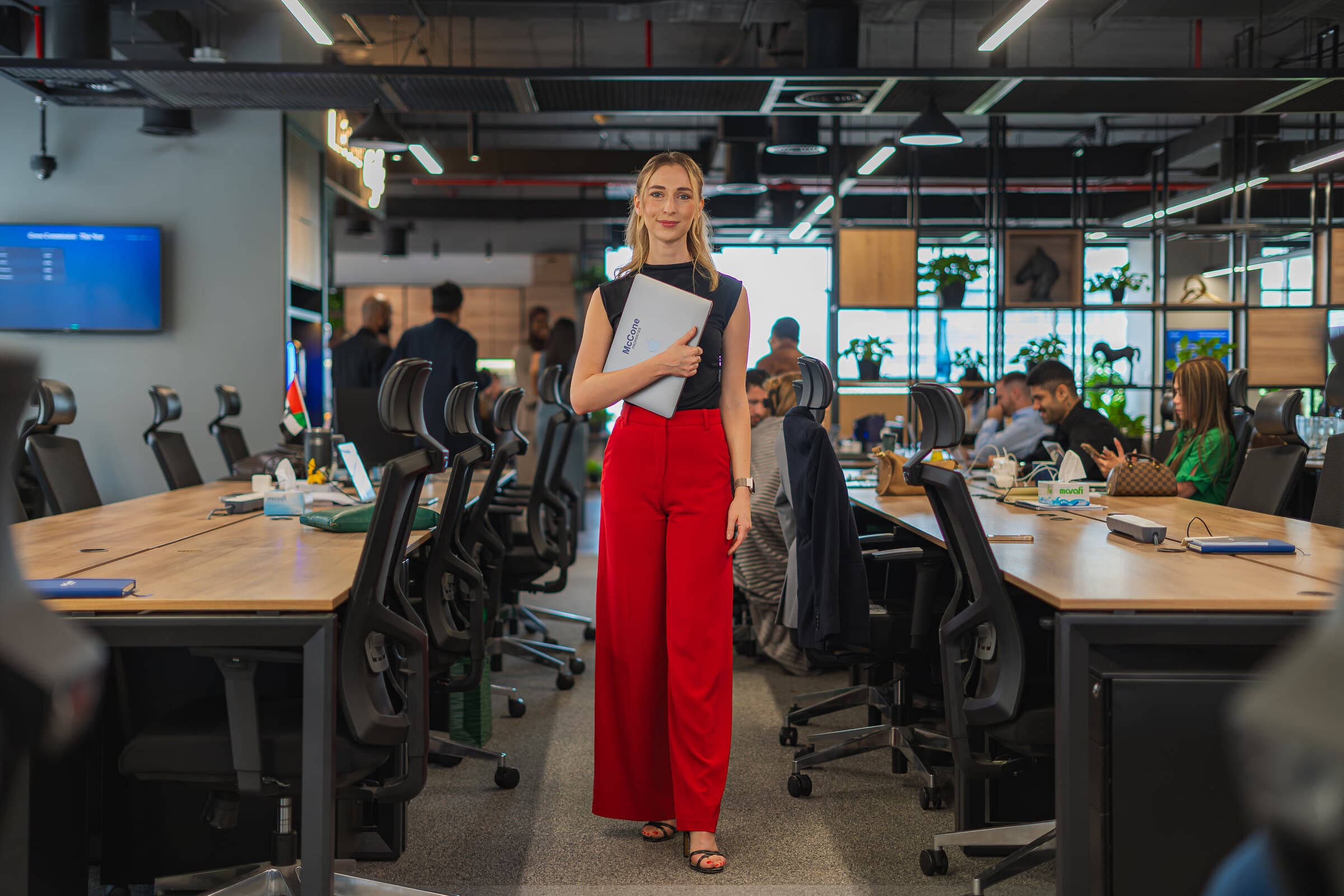 A McCone Properties agent standing on the open office floor in The Greens, with colleagues working at the desks behind her.