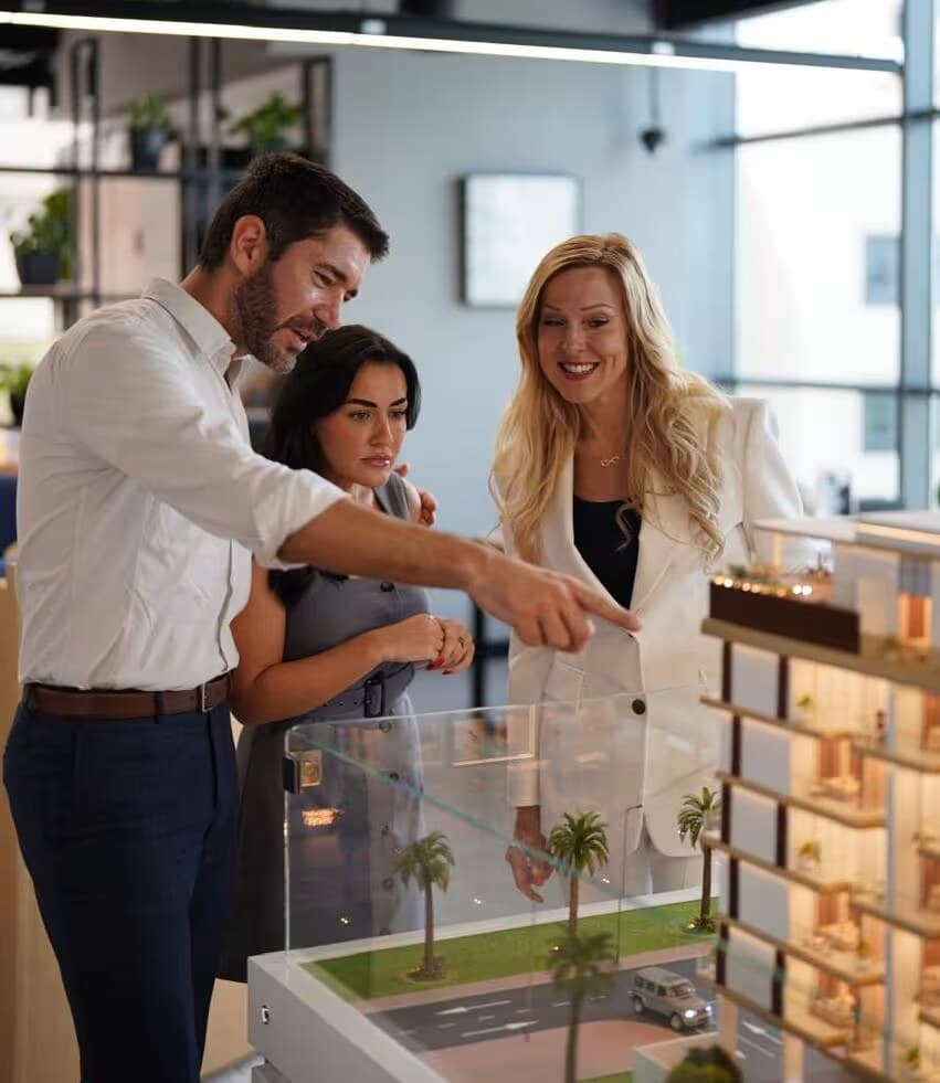Gwen De Vos met kopers bij een maquette, op het kantoor van McCone Properties in Dubai