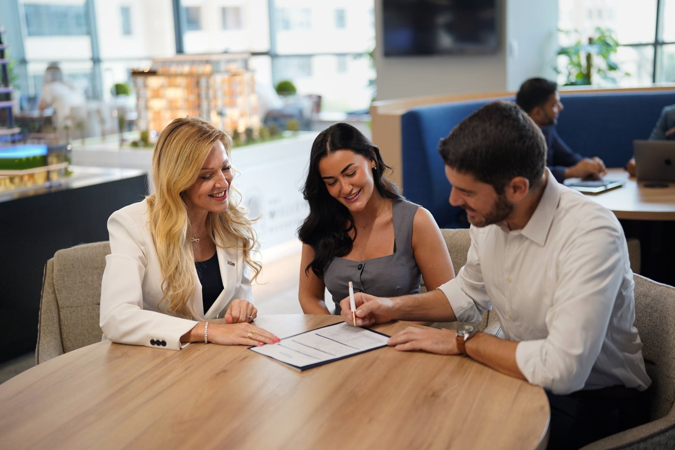A buyer signing a property contract at a table with two McCone agents