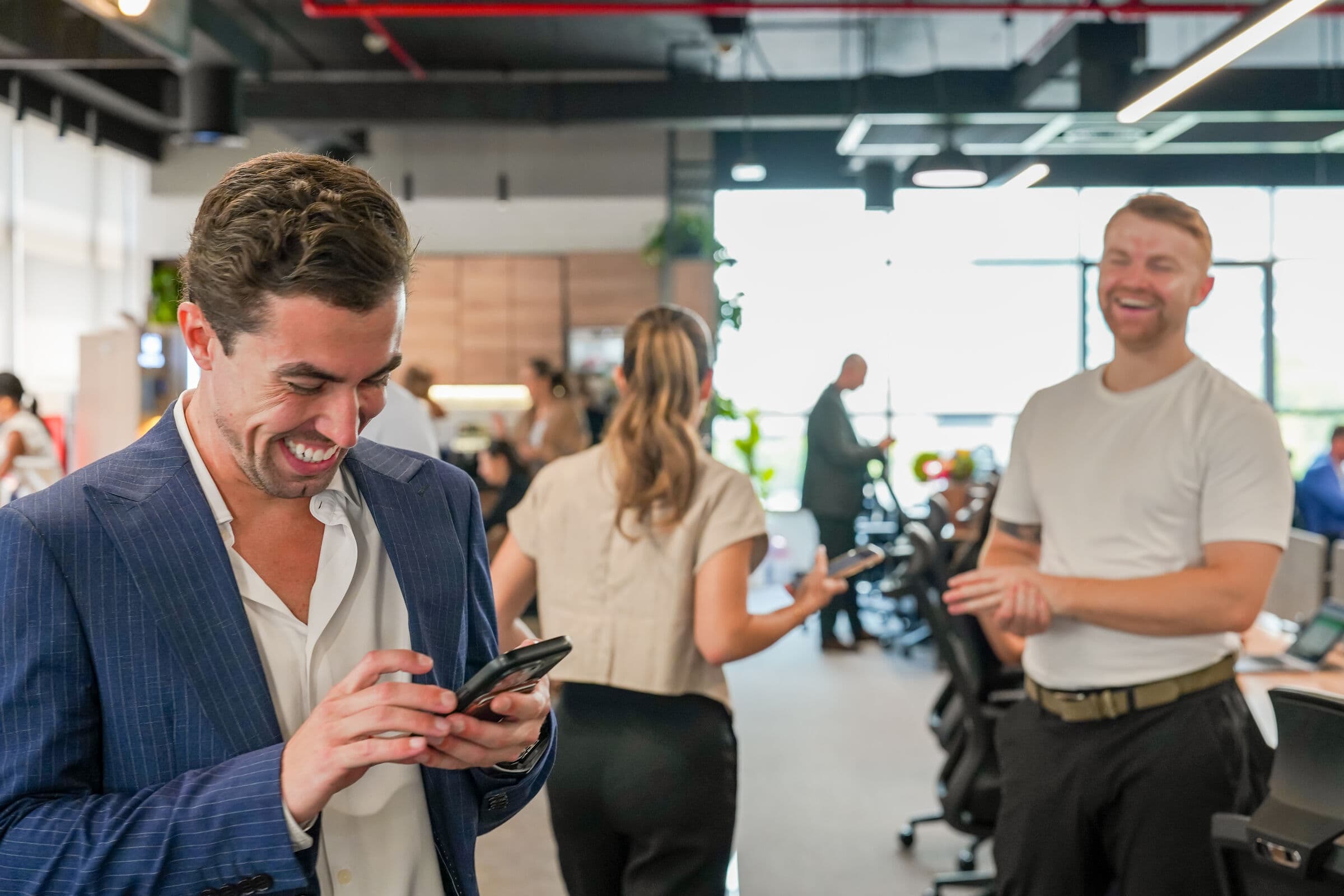 McCone Properties agents on the office floor in Dubai, one checking his phone and laughing