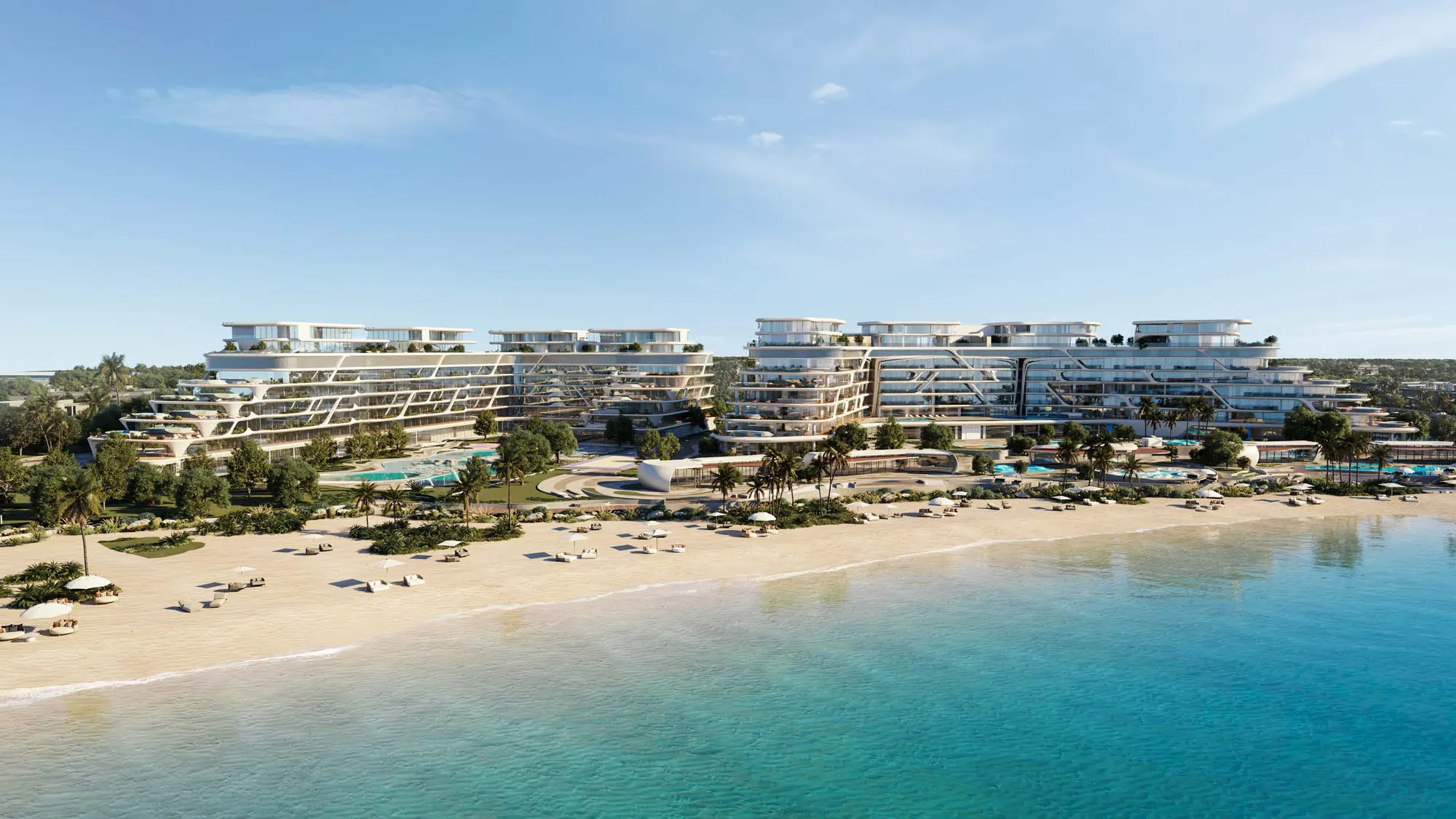 Curving terraced apartment buildings behind a sandy beach and turquoise sea