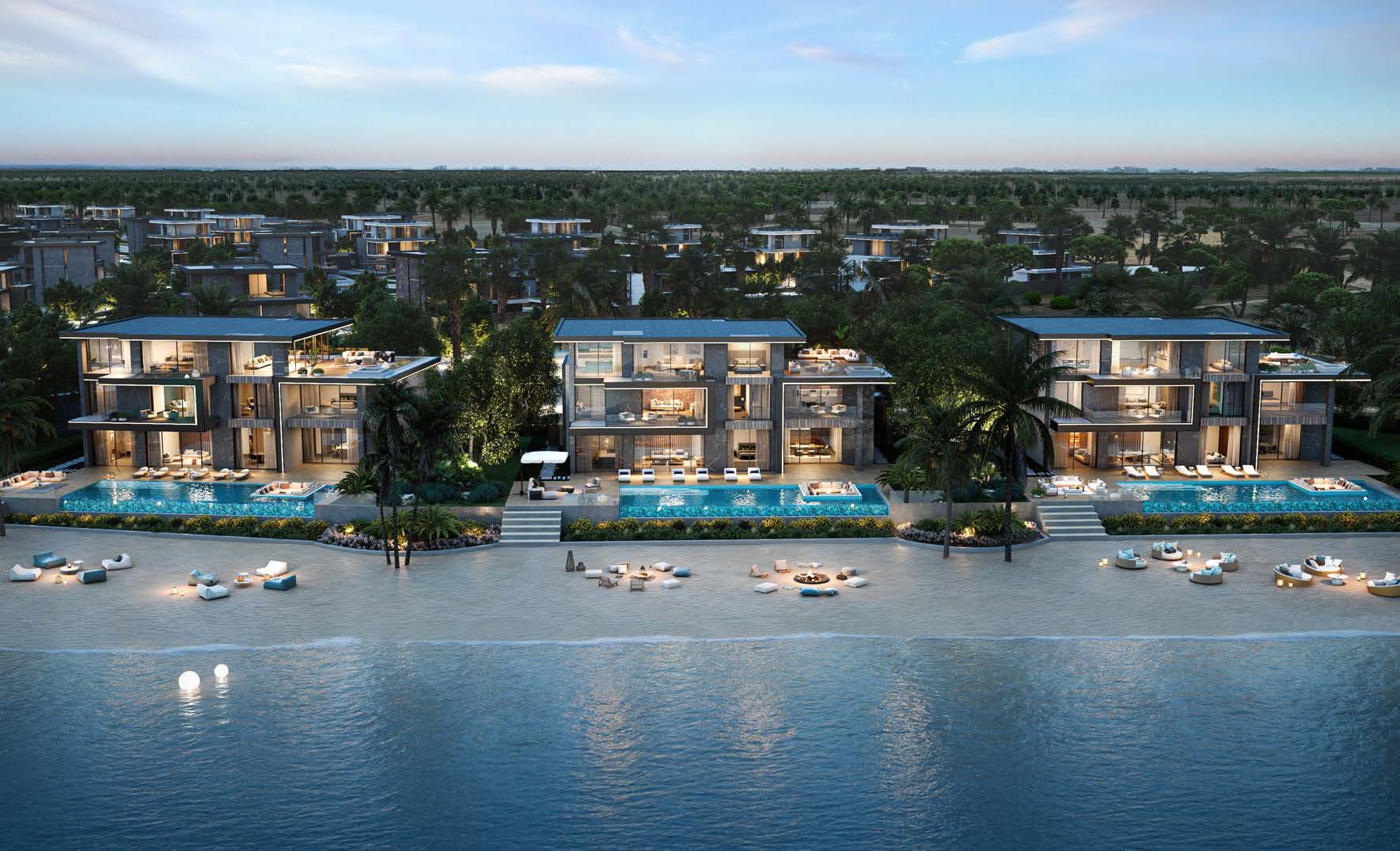 Beachfront villas lit at dusk with infinity pools above the sand