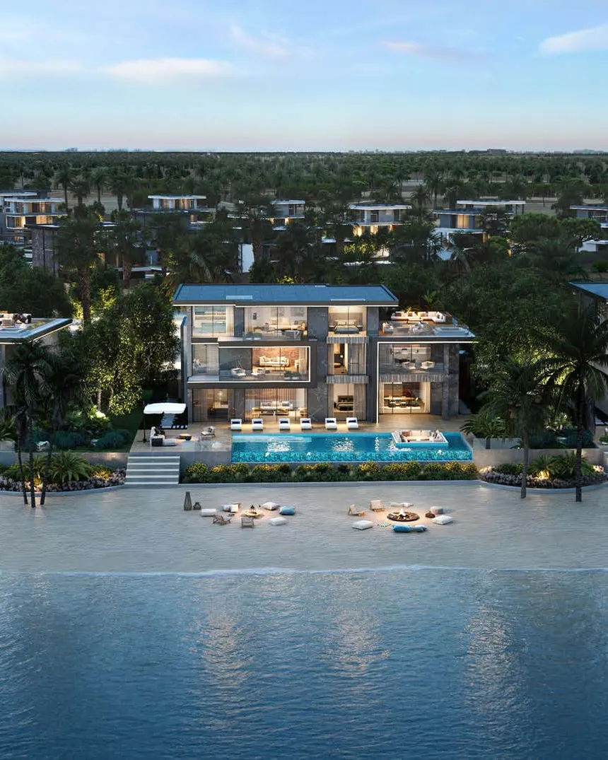 Beachfront villas lit at dusk with infinity pools above the sand