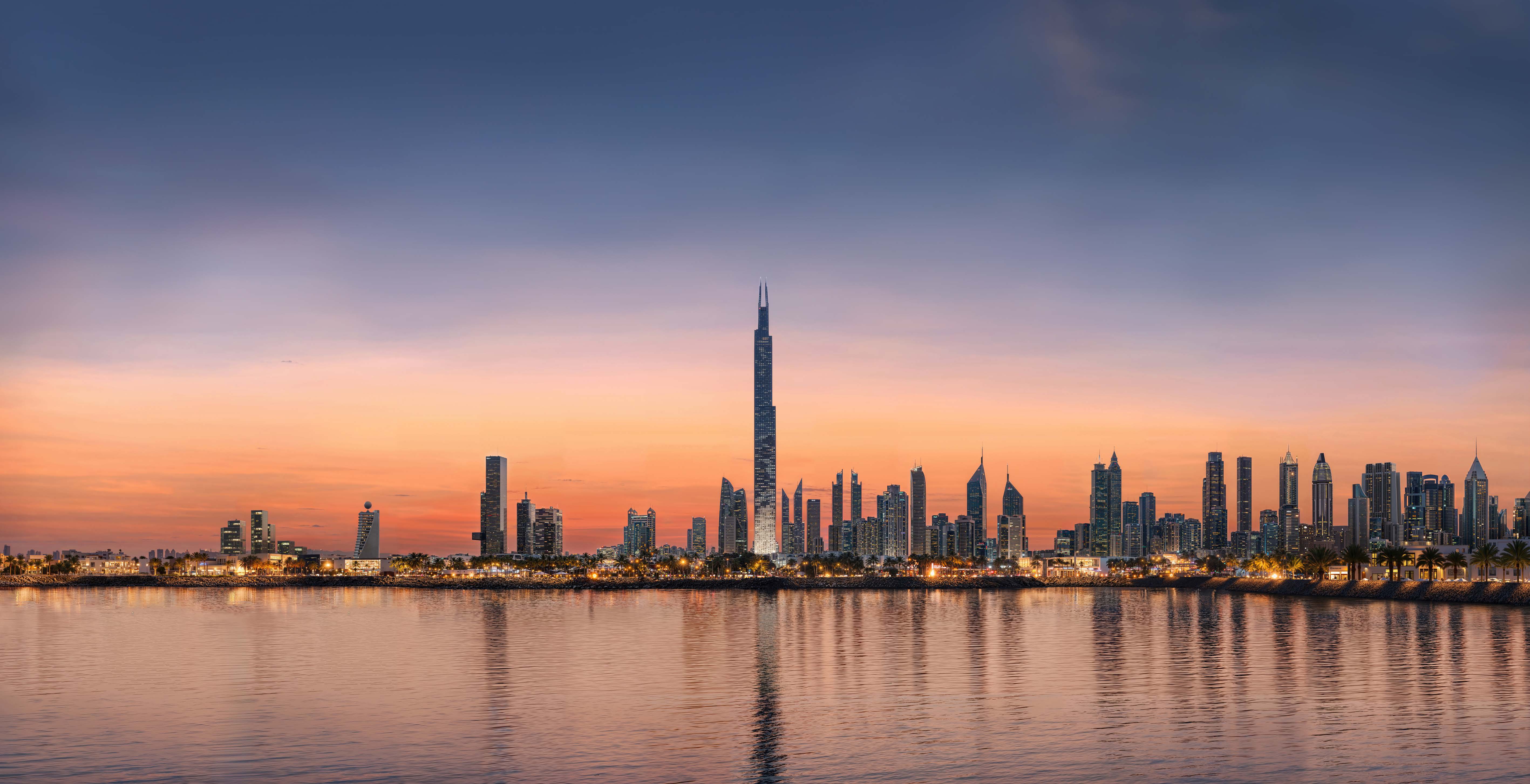 Burj Azizi over Dubai's skyline at sunset, reflected in the water