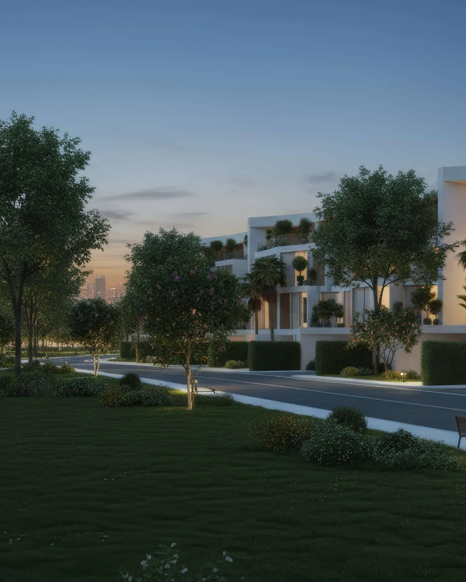 Tree-lined street and park between curved white villas at dusk