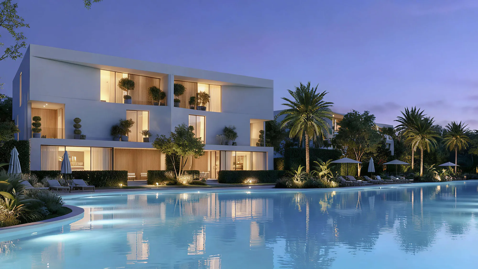 White Dune villas lit at dusk beside a wide lagoon lined with palms