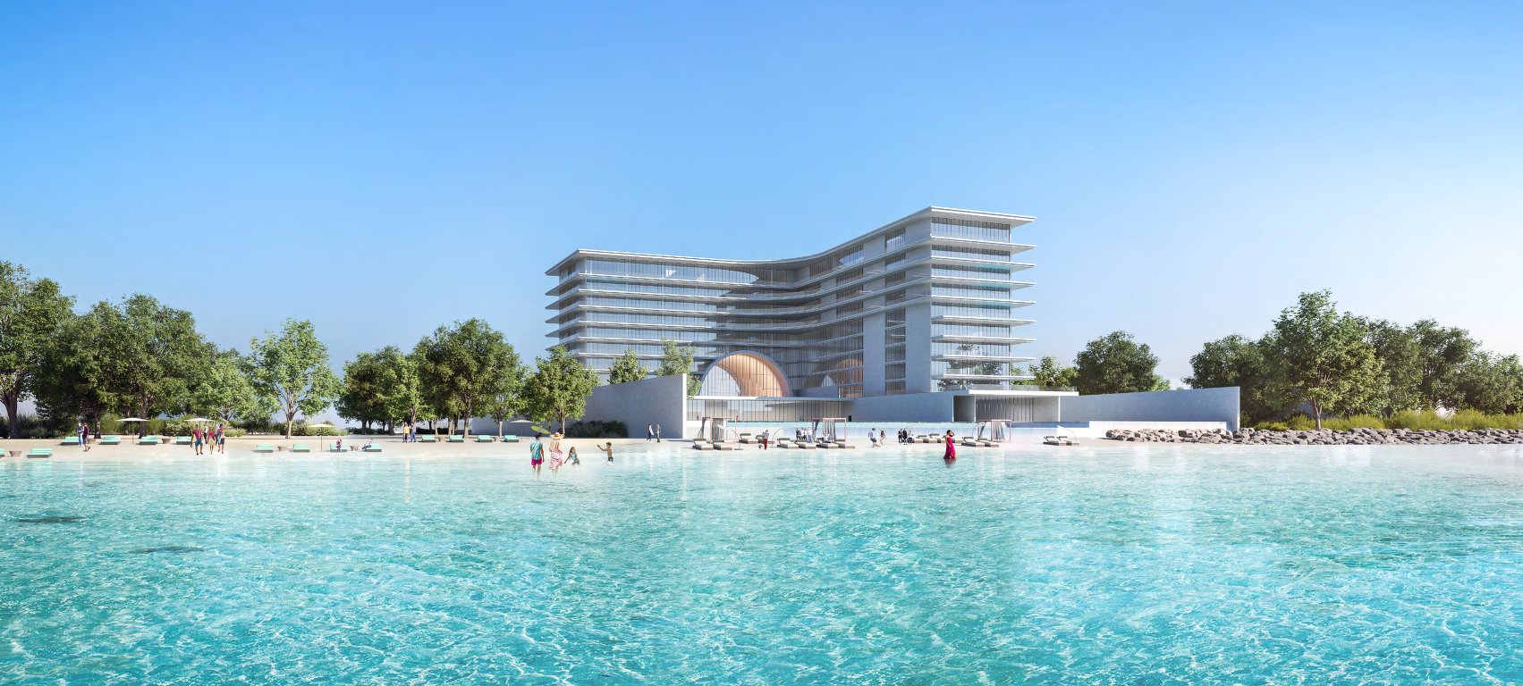 Curved terraced building behind a turquoise lagoon and sandy beach lined with trees