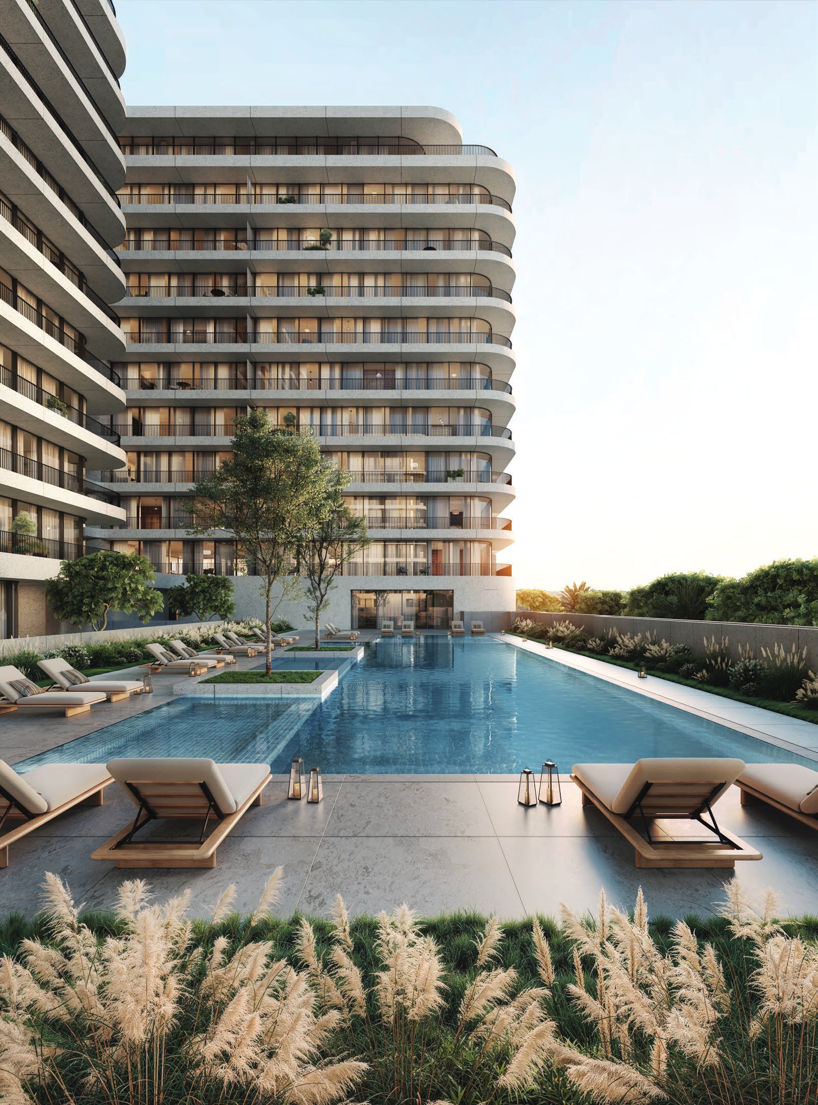 Long pool lined with sun loungers beneath a curved residential building