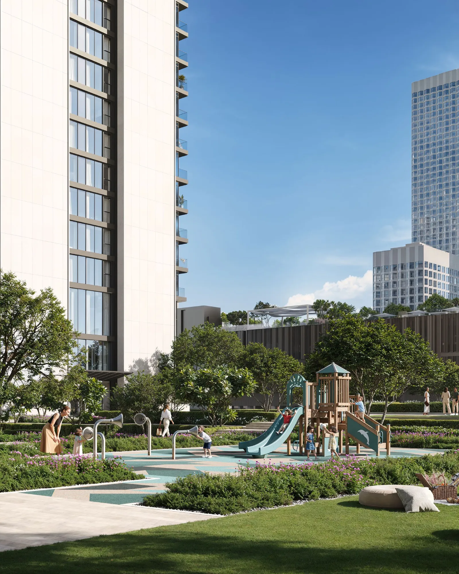 Families in a sunny garden with a playground and picnic lawn below the towers
