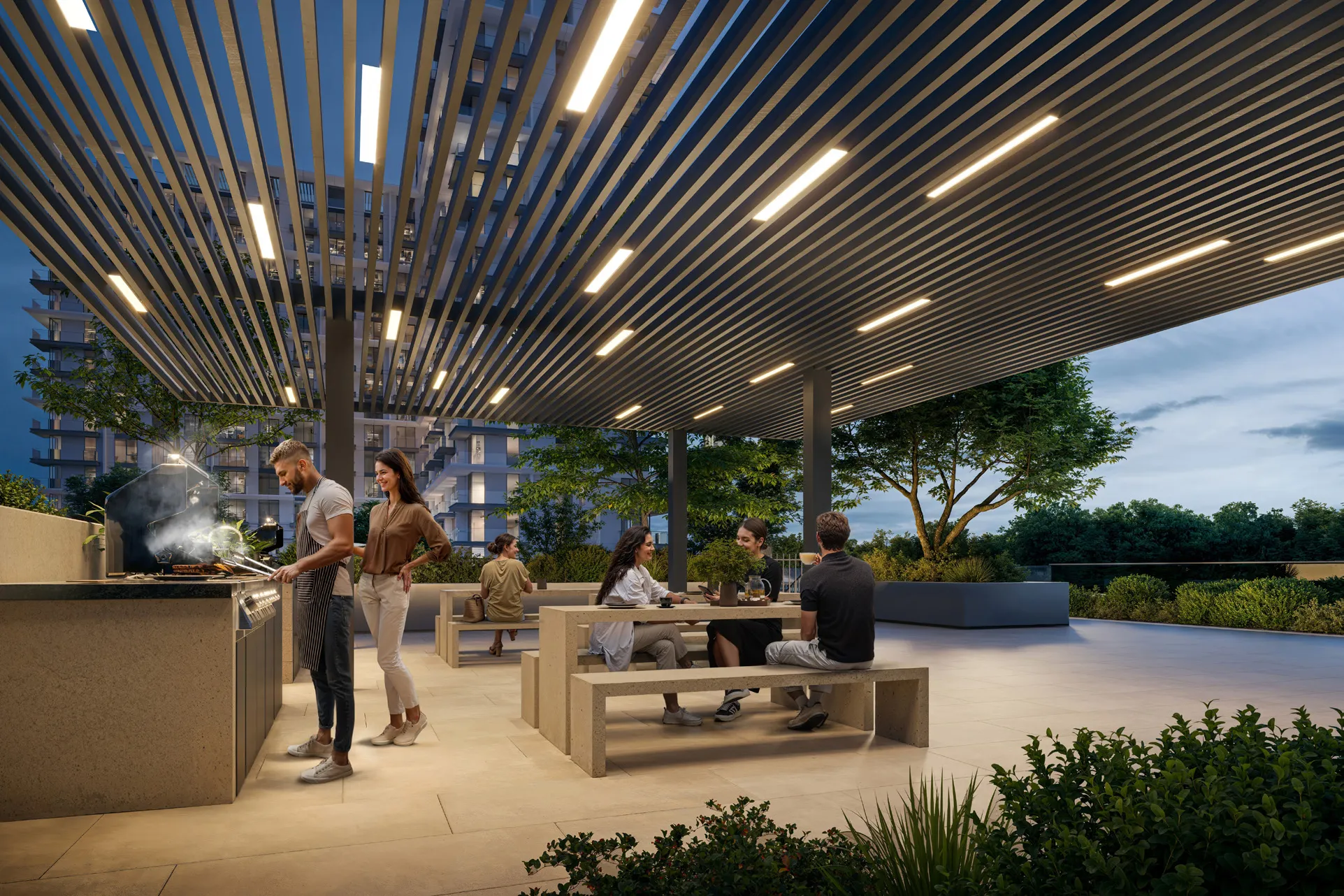 Covered barbecue terrace with grills and long stone tables at dusk
