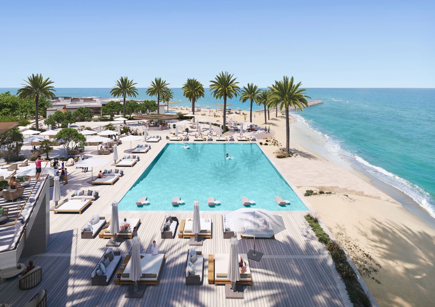 Beach club pool with loungers and palm trees beside the sea