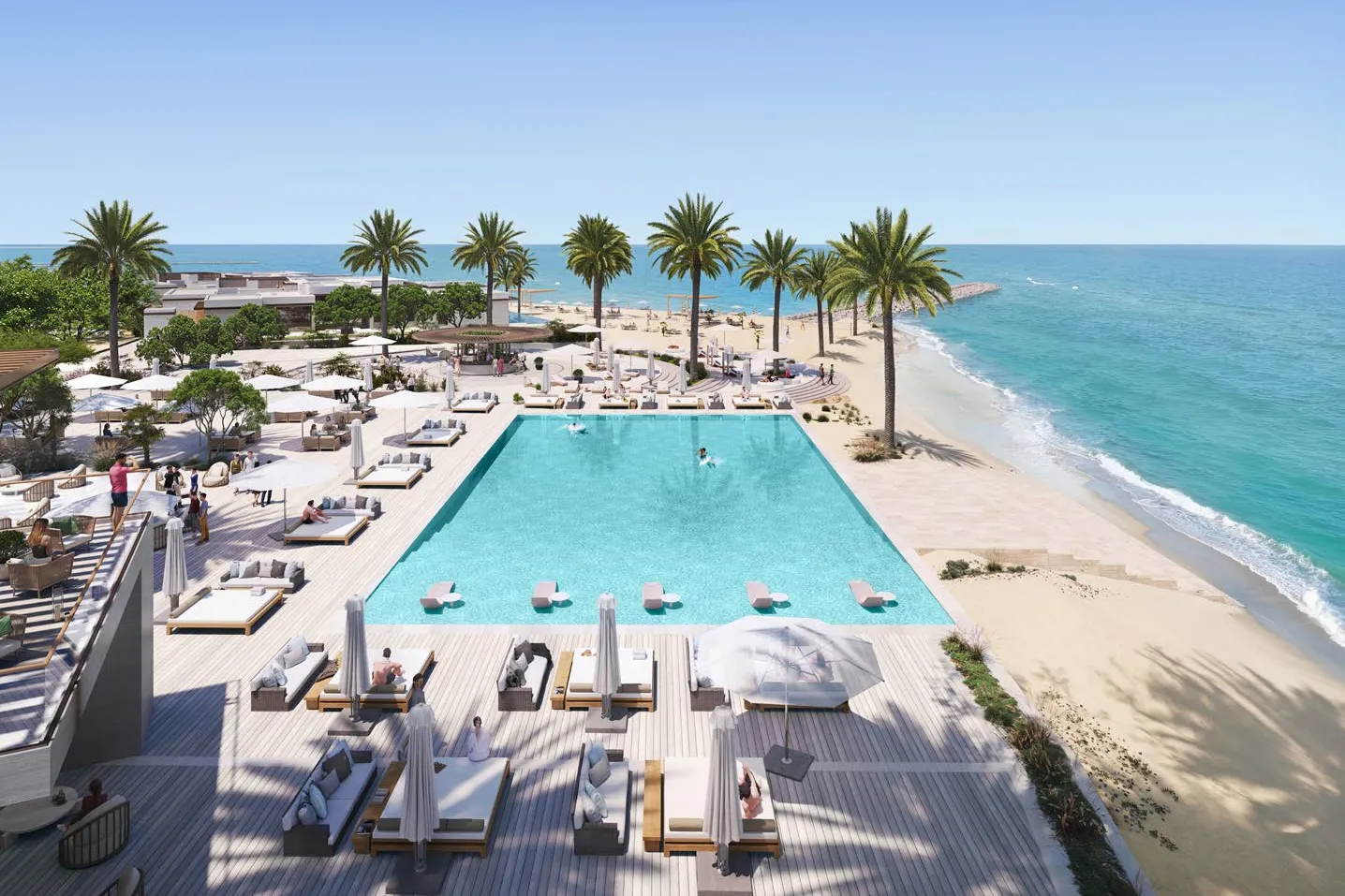 Beach club pool with loungers and palm trees beside the sea