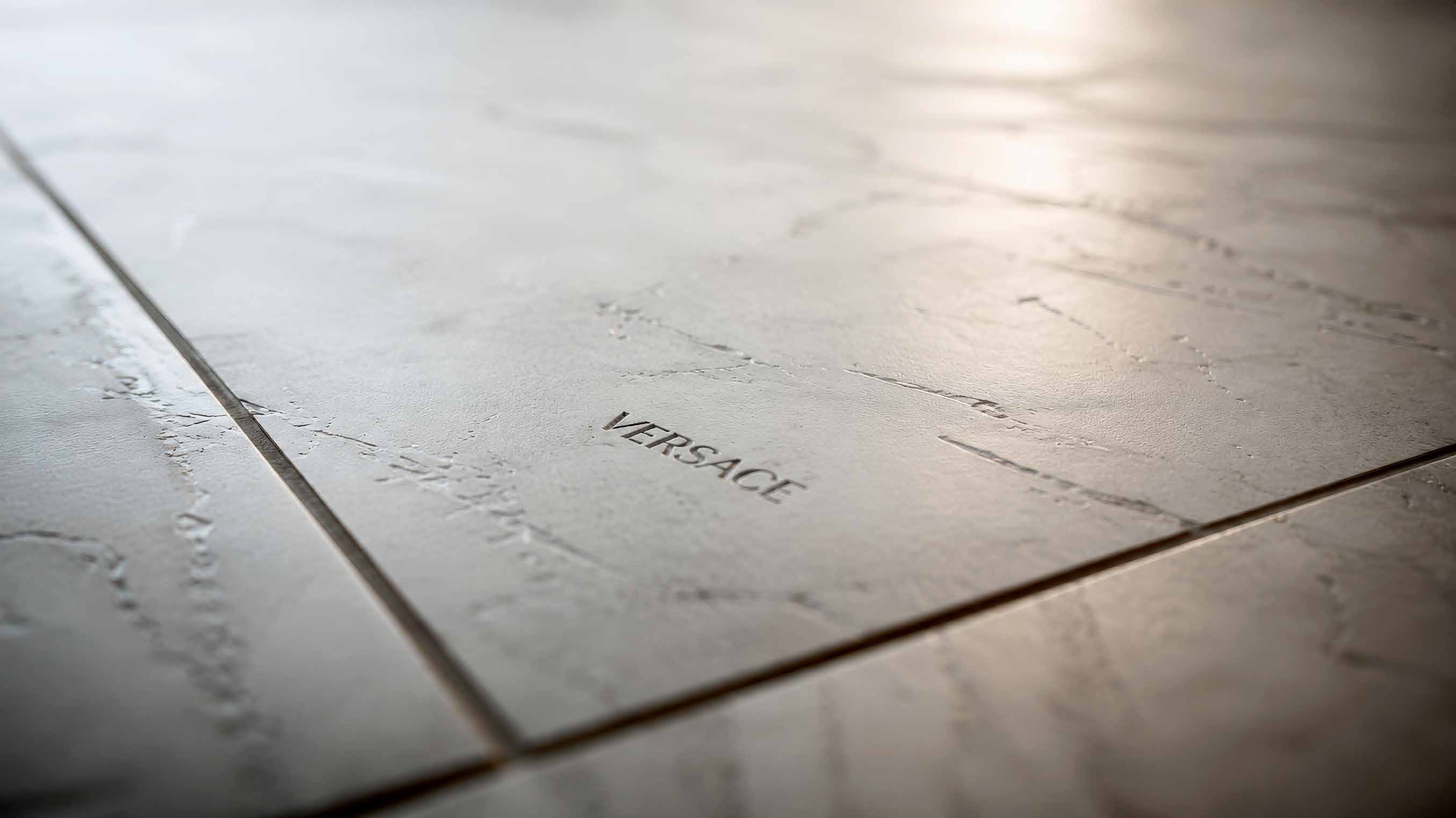 Close-up of grey stone-effect floor tiles engraved with the Versace name