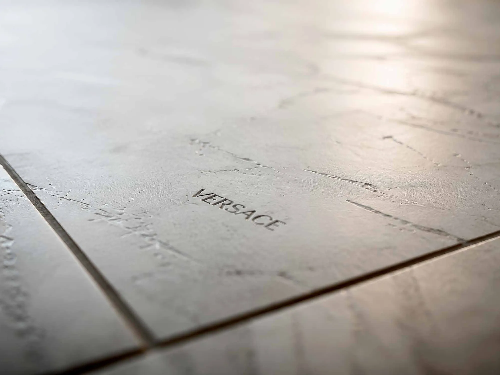 Close-up of grey stone-effect floor tiles engraved with the Versace name