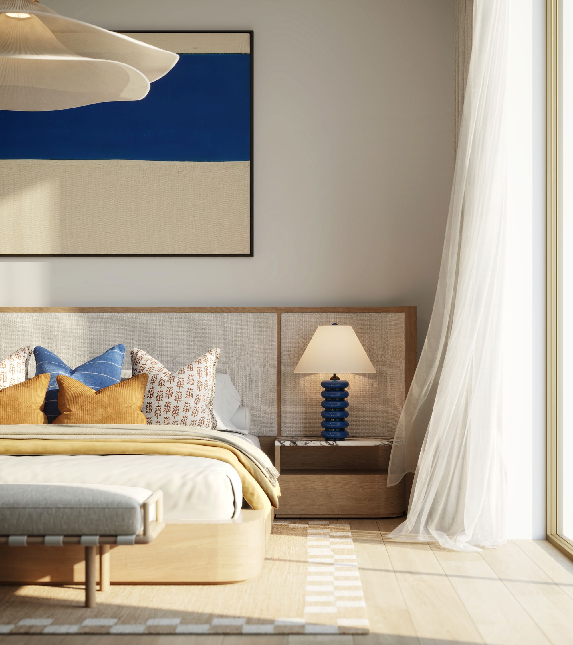 Bedroom with an upholstered headboard, blue artwork and soft natural light