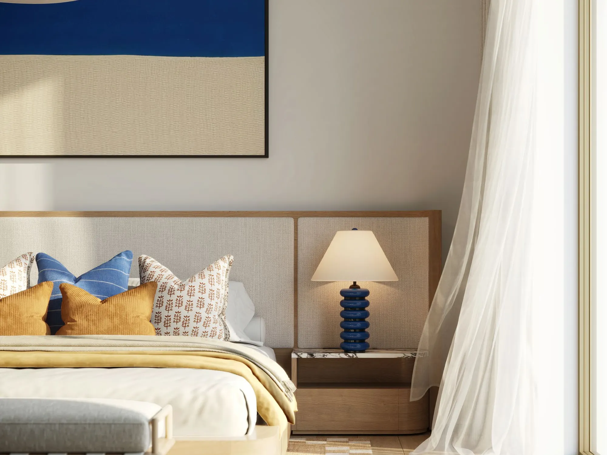Bedroom with an upholstered headboard, blue artwork and soft natural light