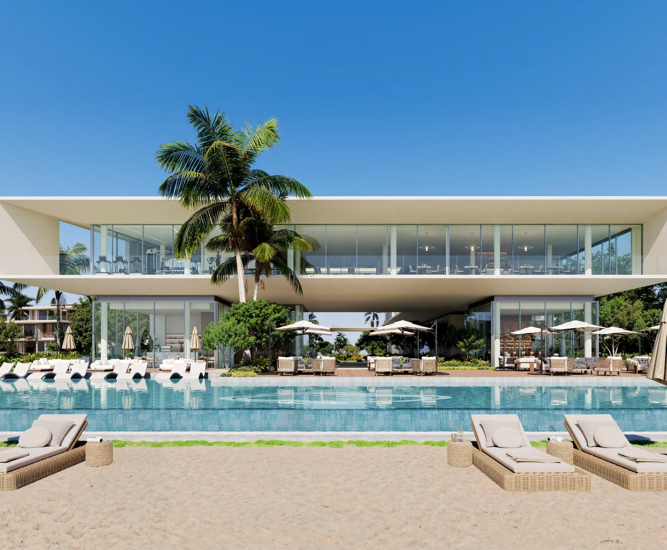 Beach club pool with loungers on the sand and a glass-fronted gym above