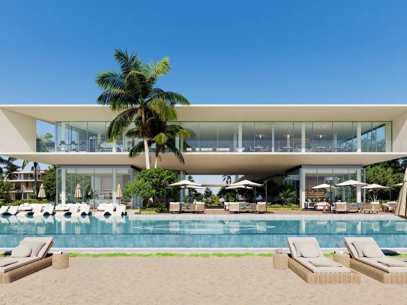 Beach club pool with loungers on the sand and a glass-fronted gym above