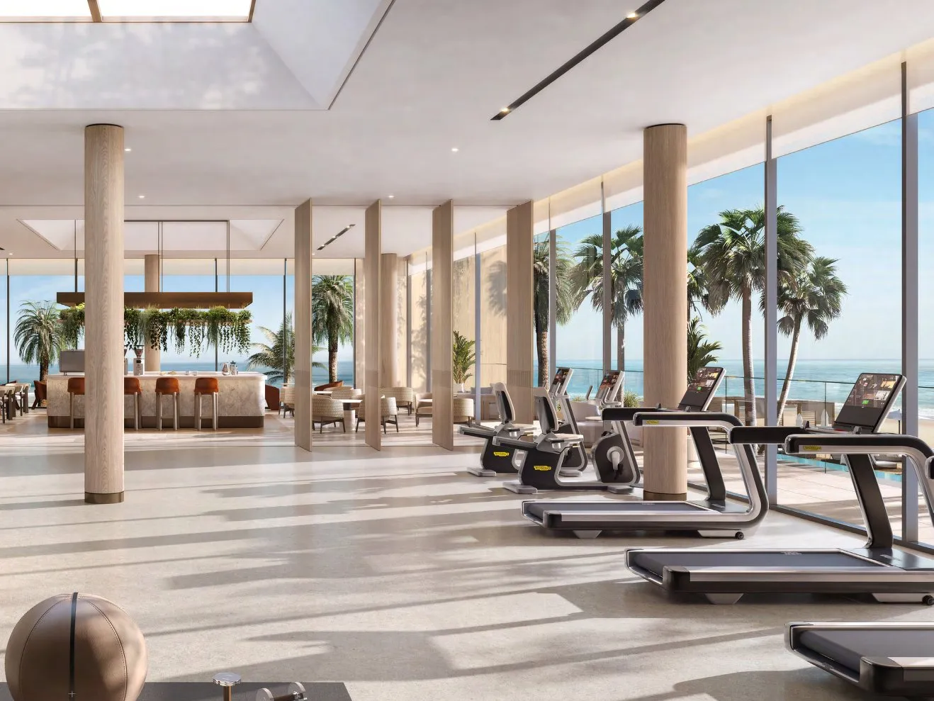 Bright gym with treadmills and a café bar facing the sea