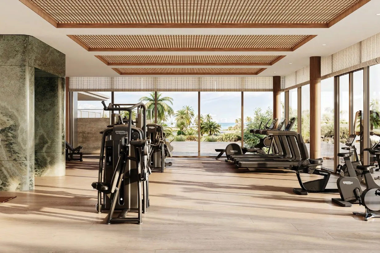 Gym with timber ceiling and glass walls opening onto palms