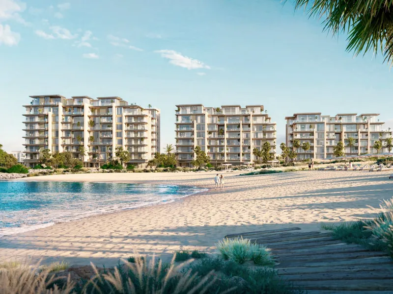 Three Solaya buildings rising behind a white sand beach and calm sea
