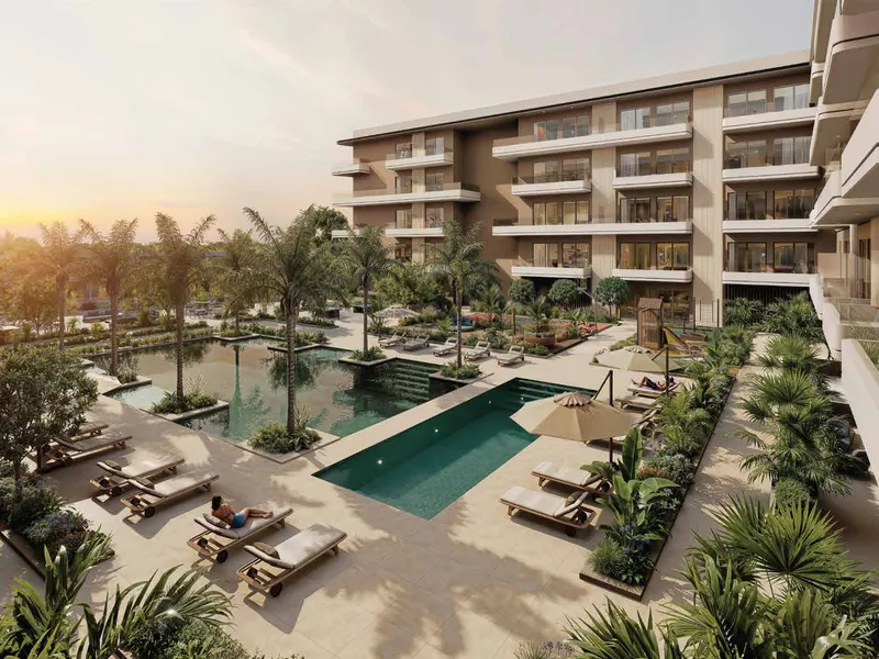 Palm-lined courtyard pools and loungers at sunset beside the residences