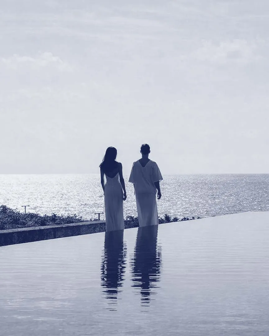 Two people at the edge of an infinity pool at dusk